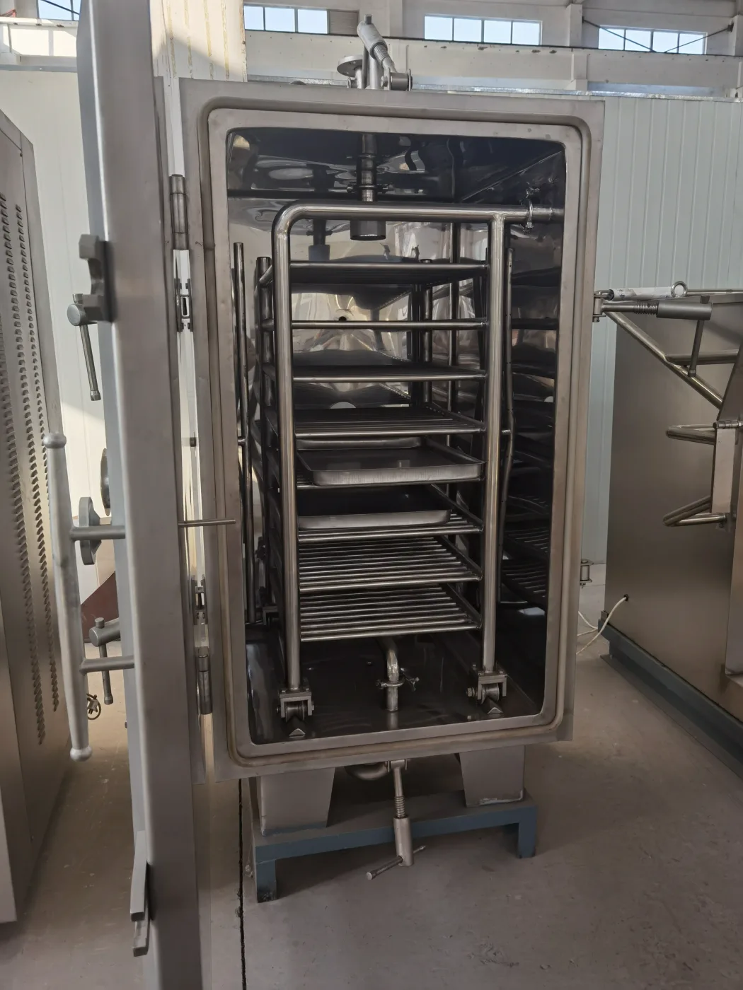 Loading trays into a vacuum shelf dryer, illustrating the manual handling that limits throughput
